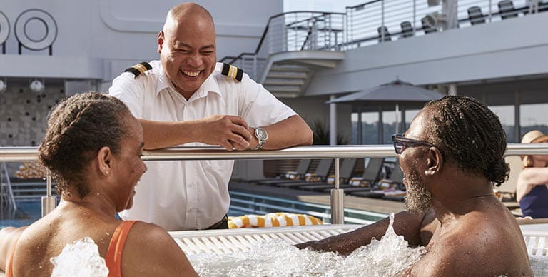 A couple in the hot tub, speaking with a crew member